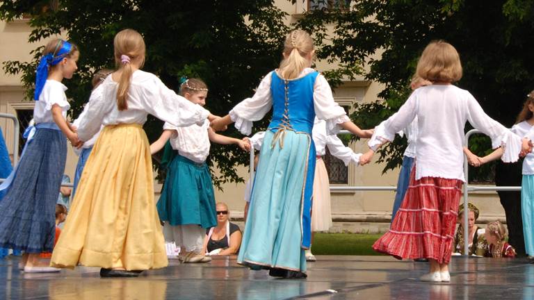 A group of young girls hold hands in a circle to dance