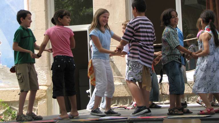 Elementary students dance in pairs on an outdoor stage