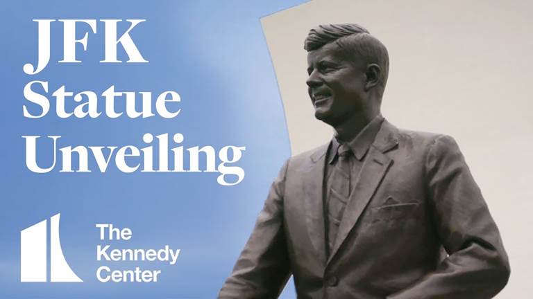Statue of JFK with sky in background and the words JFK Statue Unveiling