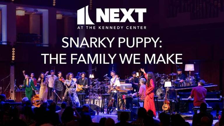 The bandmembers of Snarky Puppy on stage at the Kennedy Center with the Next logo and the words Snarky Puppy: The Family We Make